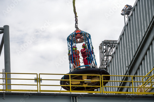 Offshore personnel being lifted with crane on a personal-transfer-basket from an oil production platform to a crew boat for crew change