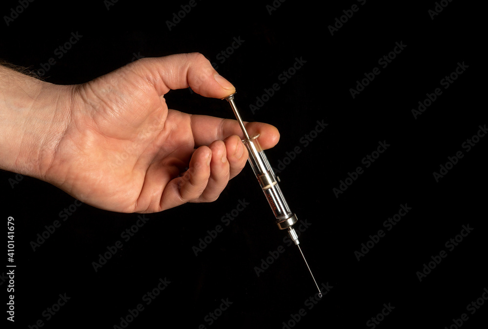 Medical syringe in man hand on black isolated background Medical syringe in man hand on black isolated background