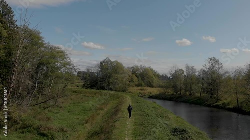 Drone 4K Footage Cloverdale of a man walking on a dike levee trail in the rural backdrop with scenic terrain and revealing a highway in the distance photo