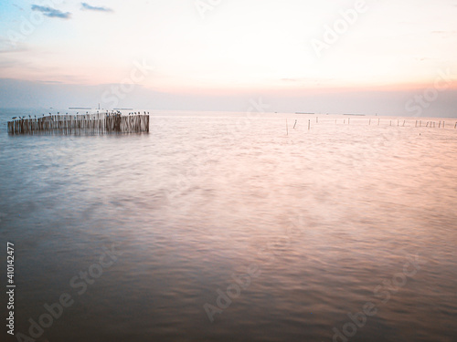 Fototapeta Naklejka Na Ścianę i Meble -  long exposure wooden pole in sea at dusk. Pastel blue and pink sky in Bangpu Thailand