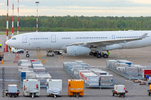Aircraft parked at the airport, in front of it is a food containers and mobile power supplies. Flight service.