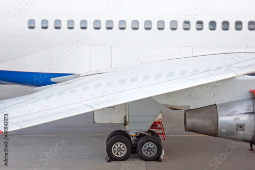 Engine on white fuselage with portholes of passenger plane, jet turbine, windows, wing, aircraft detail, aviation and aerospace industry.