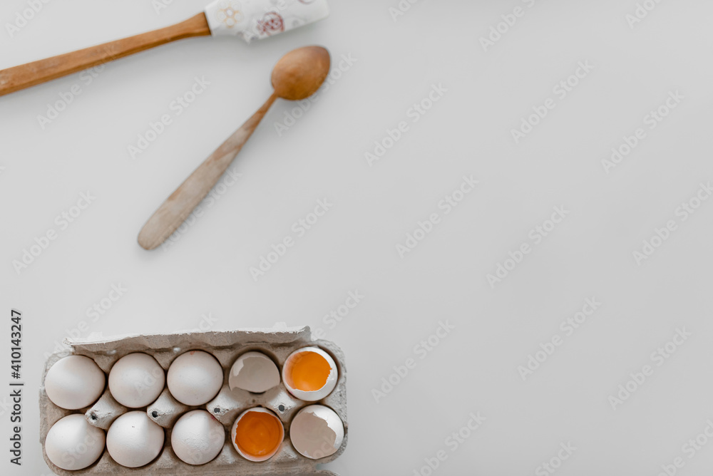Organic chicken eggs in brown paper boxes, spoon placed on a white wooden table. Raw materials and equipment for making homemade bread.Top view and copy space Organic chicken eggs in brown paper boxes, spoon placed on a white wooden table. Raw materials and equipment for making homemade bread.Top view and copy space