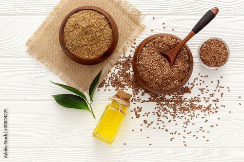 Flaxseeds in a spoon and bowl with a bottle of flaxseed oil and flaxseed flour photo