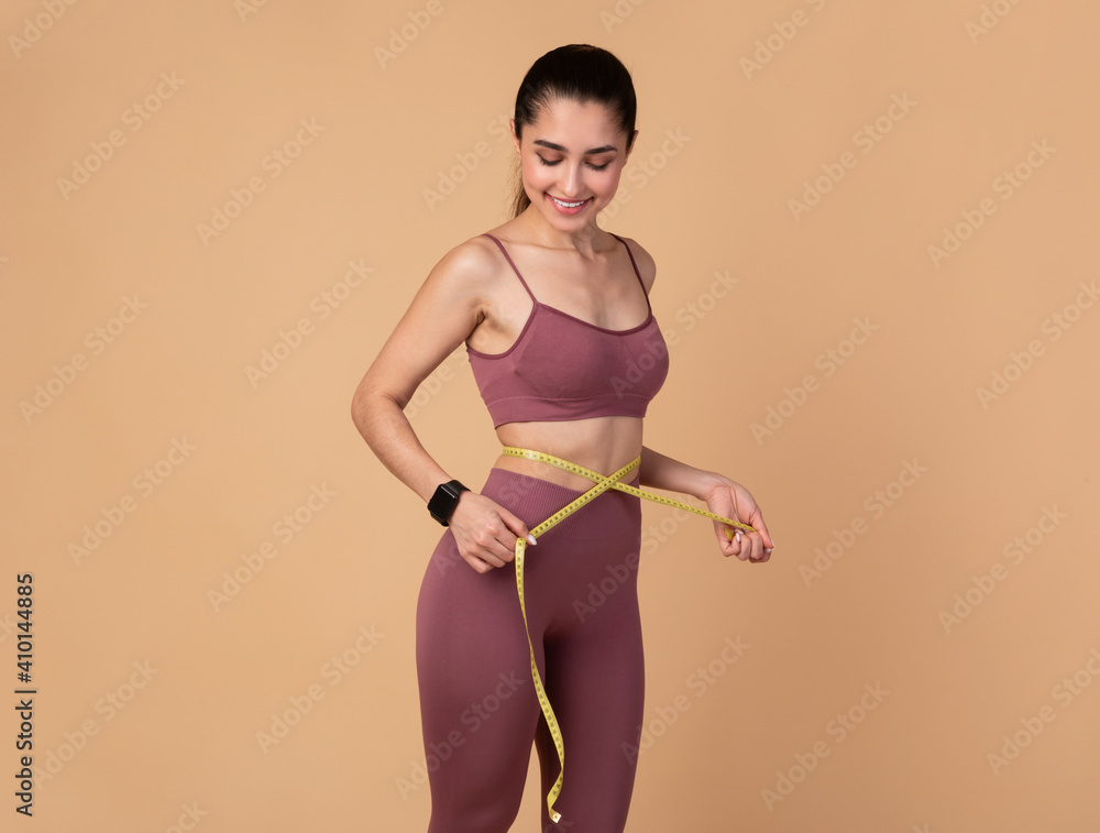 Smiling Young Woman Measuring Waist And Looking On Tape Smiling Young Woman Measuring Waist And Looking On Tape