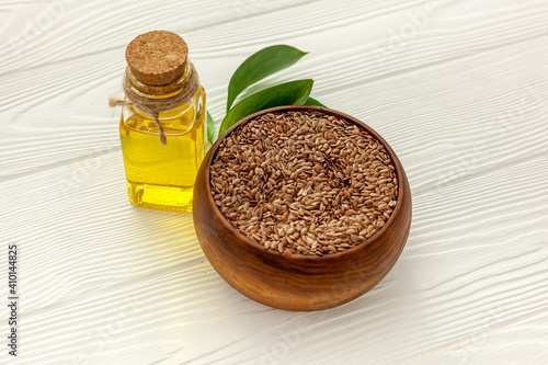 Flax seeds in a spoon and bowl with a bottle of flaxseed oil