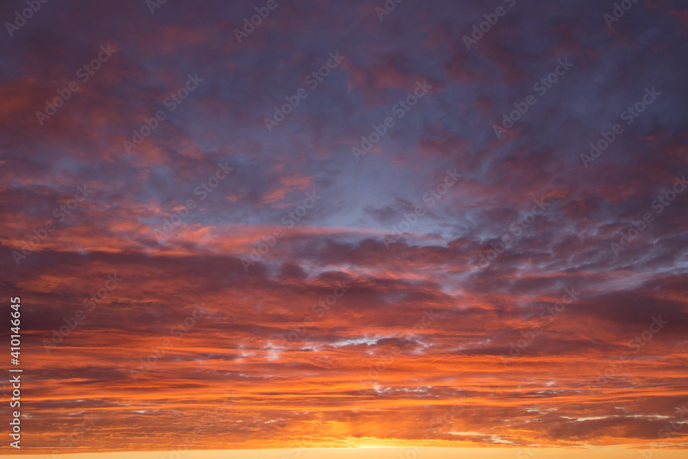Obraz premium Epic Dramatic sunrise, sunset orange red yellow pink clouds against blue sky background texture