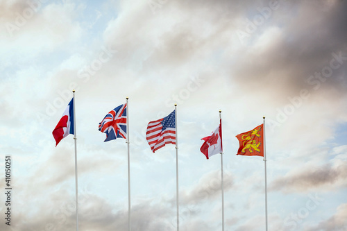 World War Two D-Day flags of allied military forces nations Canada France Great Britain and America flying at sunset on French town Arramanches Gold Beach in Normandy Europe
