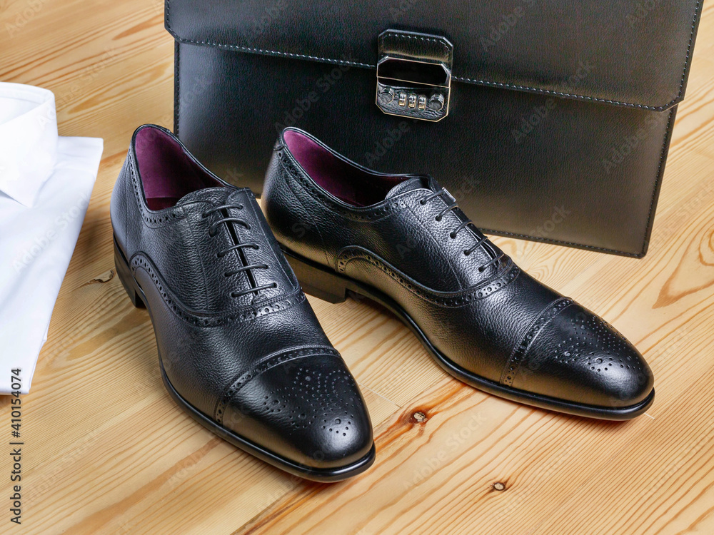 Men's shoes in classic style on the background of a white shirt and a business briefcase