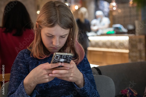 teenager girl playing the phone in a cafe, horizontal