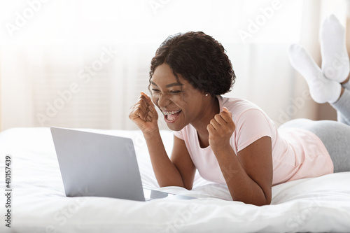 Emotional black woman looking at laptop screen and screaming