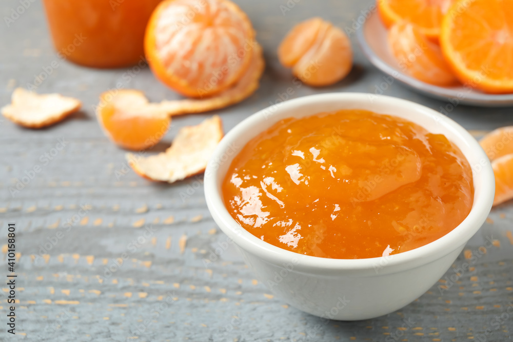 Tasty tangerine jam in bowl on grey wooden table. Space for text Tasty tangerine jam in bowl on grey wooden table. Space for text