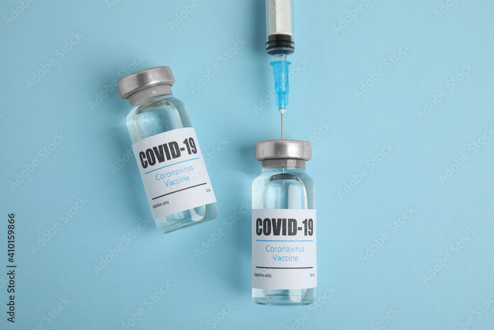Filling syringe with coronavirus vaccine on light blue background, flat lay Filling syringe with coronavirus vaccine on light blue background, flat lay