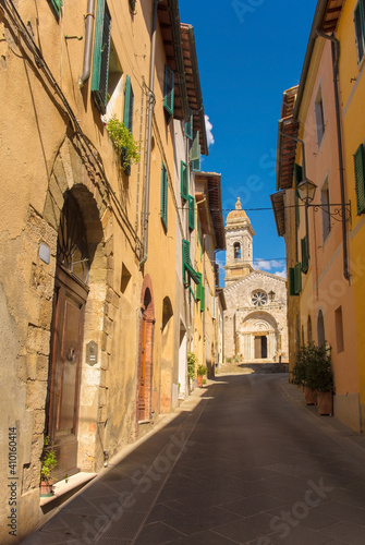 A residential road leads to the Collegiata dei Santi Quirico e Giulitta in the historic medieval village of San Quirico D'Orcia, Siena Province, Tuscany, Italy 