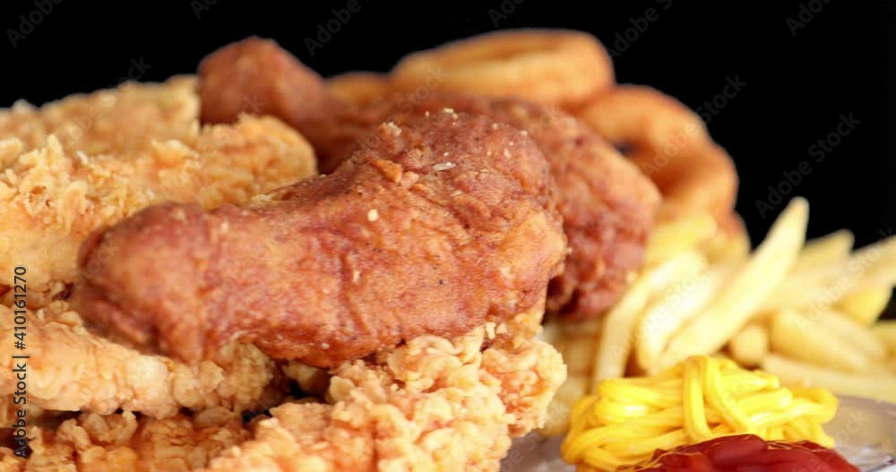 Macro view of Tasty french fries and crispy chicken nuggets with mustard and ketchup at black background Macro view of Tasty french fries and crispy chicken nuggets with mustard and ketchup at black background