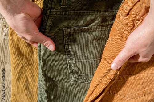 Hands select corduroy trousers lying on the counter. Shopping. 