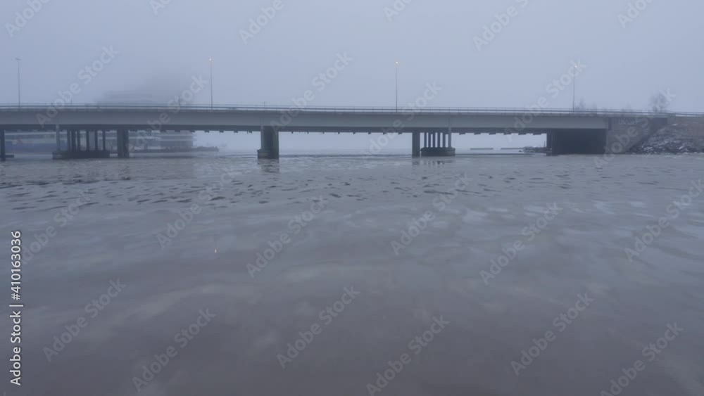 Aerial drone shot flying low over river towards and under main road bridge Aerial drone shot flying low over river towards and under main road bridge