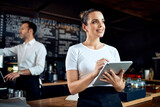 Portrait of restaurant manager standing with digital tablet at cafe