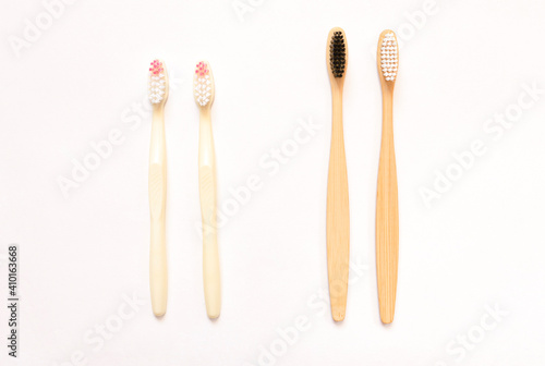 Natural bamboo toothbrushes and plastic brushes on a white background. Choose between plastic or wooden toothbrushes. A concept of a plastic-free future and an environmental friendliness. Copy space. 
