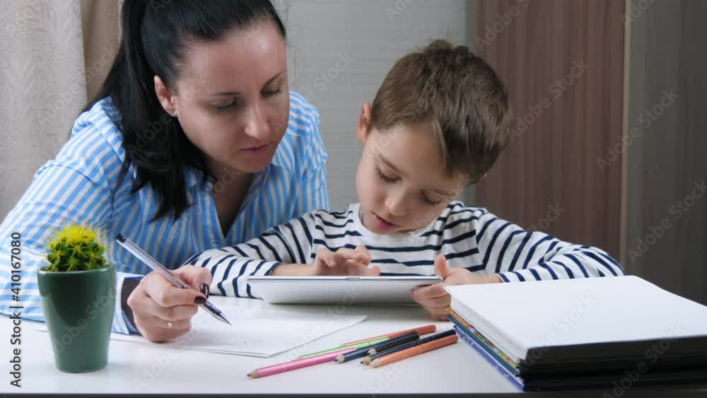 The concept of distance education. Lockdown. Mother and child spend time studying. The child uses the tablet to study. The concept of distance education. Lockdown. Mother and child spend time studying. The child uses the tablet to study.