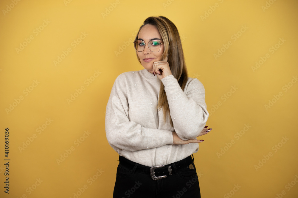 Pretty woman with long hair with serious face thinking about question, very confused idea against yellow wall Pretty woman with long hair with serious face thinking about question, very confused idea against yellow wall