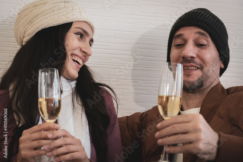 young caucasian couple with smiling face sitting togerther on couch and drinking red wine at home in winter time. happy family concept photo