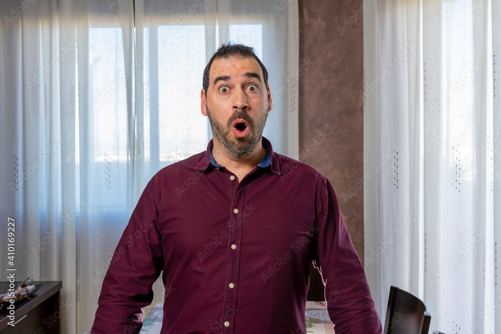 Fototapeta premium Young handsome bearded man wearing a shirt looking scared and surprised with shocked and astonishing expression