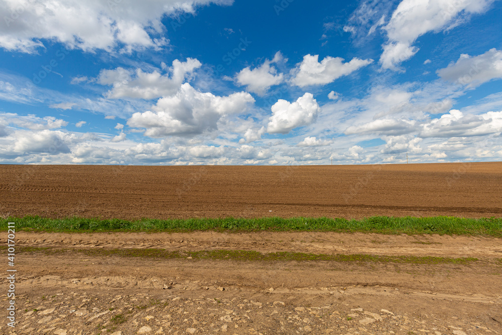 a plowed field against the sky with clouds. Spring sunny day a plowed field against the sky with clouds. Spring sunny day
