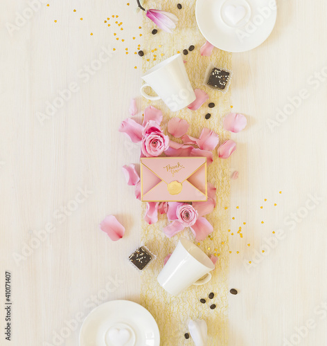 Coffee concept for lovers. Romantic morning still life with cups of coffee, sweets, a gift box and rose petals on white background. Valentine's Day. Little moments of big love. Top view