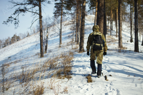 Traveller with a backpack walking in a mountainous area overgrown with coniferous forest, rear view, close-up.