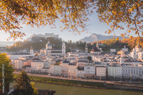 Early morning view of Salzburg, Austria and the Salzach River with autumn leaves entering the frame from the top.