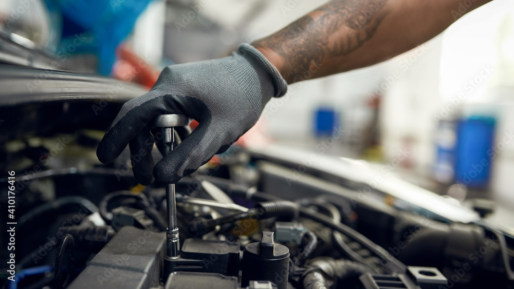 Car service station worker screwing nuts on machine engine