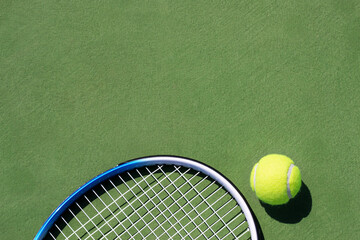 Tennis racket and tennis ball on court.