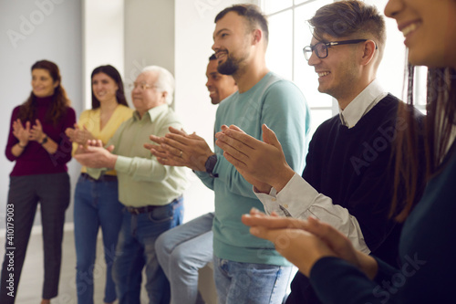 Grateful audience applauding warmly and showing their appreciation to speaker. Happy diverse people clapping hands and smiling, thanking coach for interesting presentation in group meeting