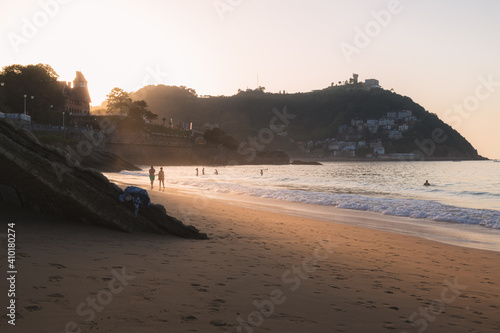 A distant silhouette of a couple enjoying the last bit of sunlight on an evening stroll along Ondaretta Beach in San Sebastian, Spain. photo