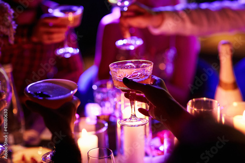 Close up of people drinking cocktails in restaurant. People having good time, cheering and drinking cold cocktails, enjoying friendship together in restaurant, close up view on hands.