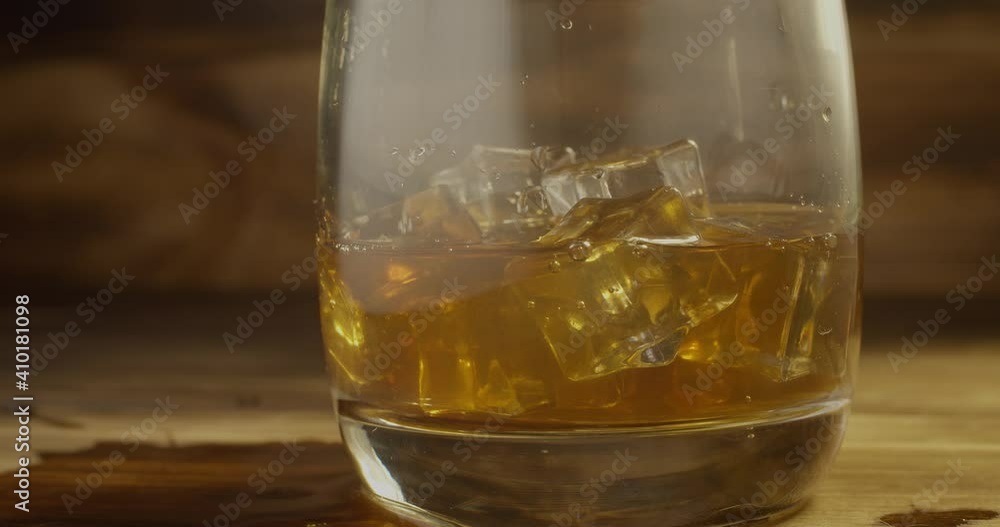 whiskey spilling past a glass of ice.
Sloppy pouring whiskey into a glass with ice on the background of a wooden bar whiskey spilling past a glass of ice.
Sloppy pouring whiskey into a glass with ice on the background of a wooden bar