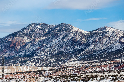 Large mountain range covered in bushes and snow on clear day in rural New Mexico