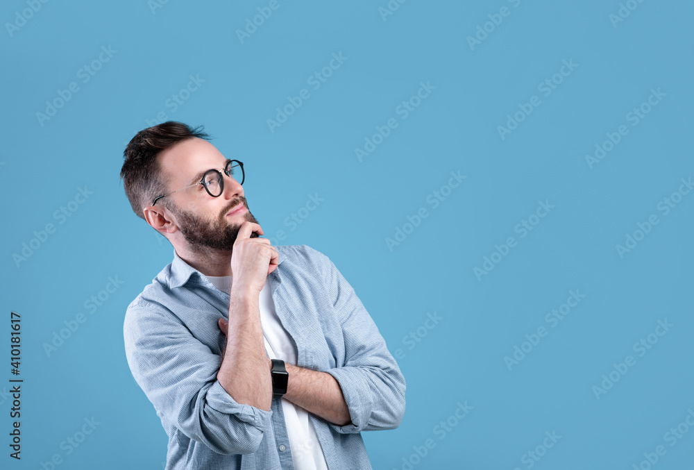Pensive Caucasian guy thinking over decision or problem, looking at empty space over blue studio background Pensive Caucasian guy thinking over decision or problem, looking at empty space over blue studio background