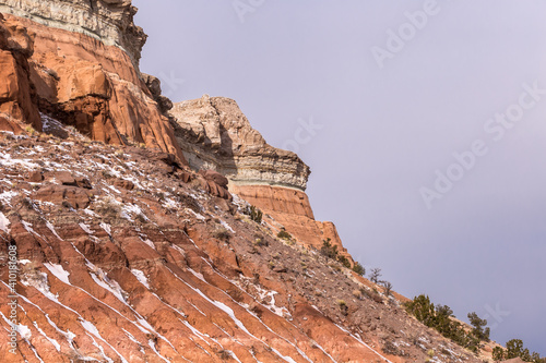 Streaks of snow along red rock mountain face on clear day in rural New Mexico