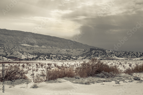 Gloomy photo of storm approaching snow covered mountain range in rural New Mexico