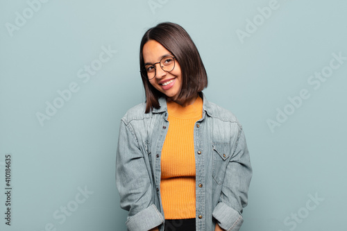 young hispanic woman smiling cheerfully and casually with a positive, happy, confident and relaxed expression