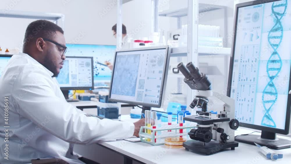 Professional African-American scientist is working on a vaccine in a modern scientific research laboratory. Genetic engineer workplace. Futuristic technology and science concept. Professional African-American scientist is working on a vaccine in a modern scientific research laboratory. Genetic engineer workplace. Futuristic technology and science concept.