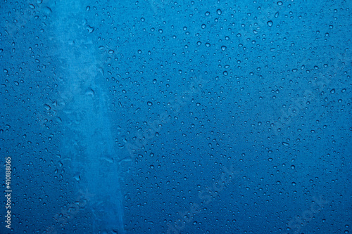 Rain water droplets accumulated on the surface of blue fabric umbrella close up detail shot