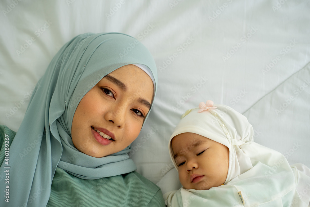 Asian Muslim young beautiful mother with baby new born on bed wearing HIJAB Asian Muslim young beautiful mother with baby new born on bed wearing HIJAB