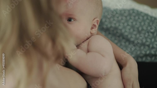 Close view of mother breastfeeds and lulls insatiable baby in room