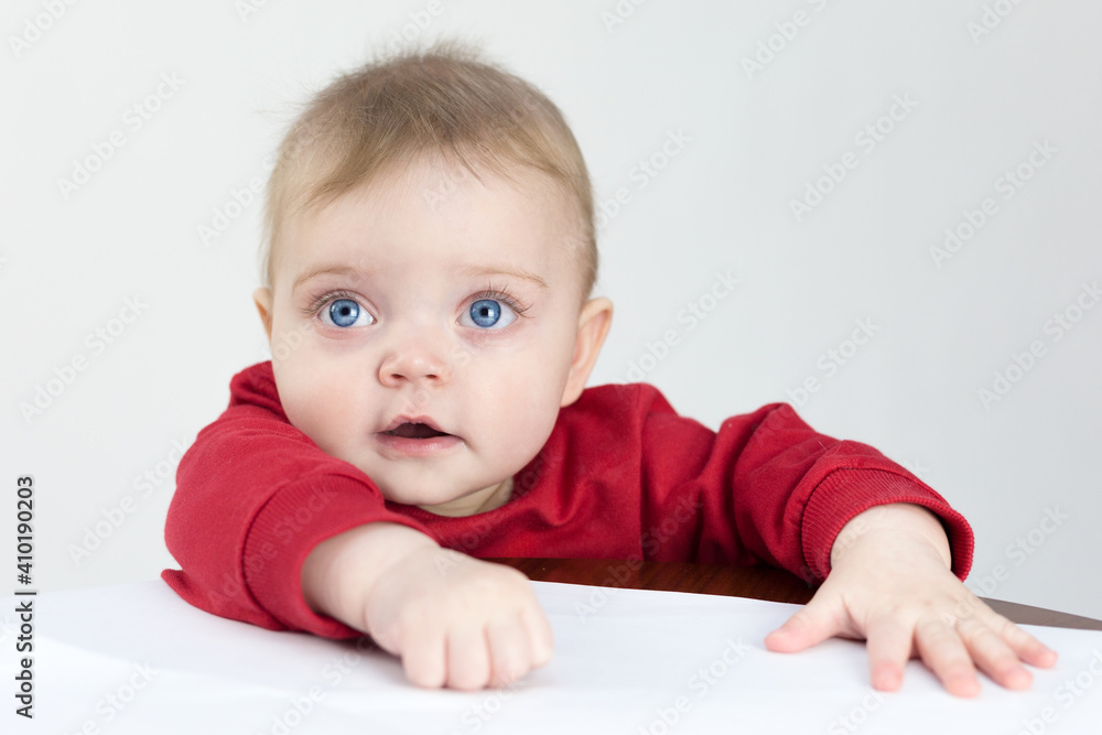 A small child is standing at table waiting to be fed. A small child is standing at table waiting to be fed.
