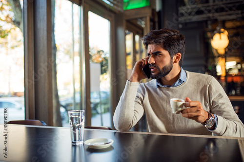 Handsome young Turkish man drinking coffee and speaking on the phone