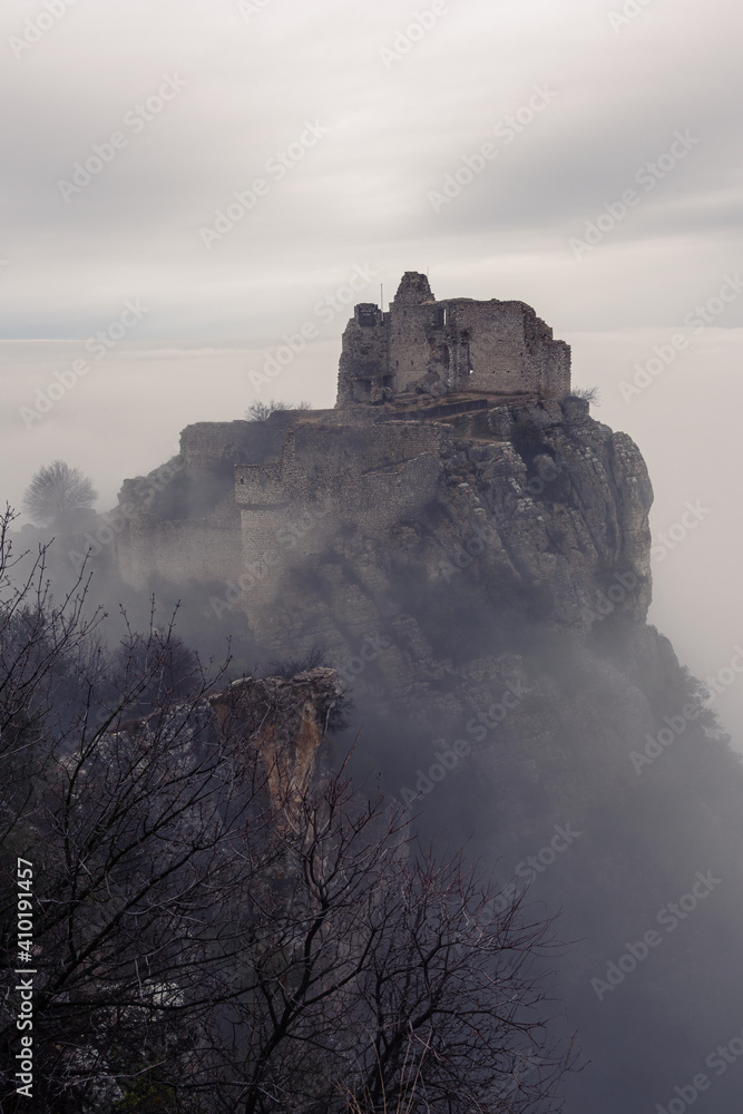 French winter landscapes. Stunning panoramic view of castle ruins Crussol. Foggy mountain landscape. Sea of clouds.