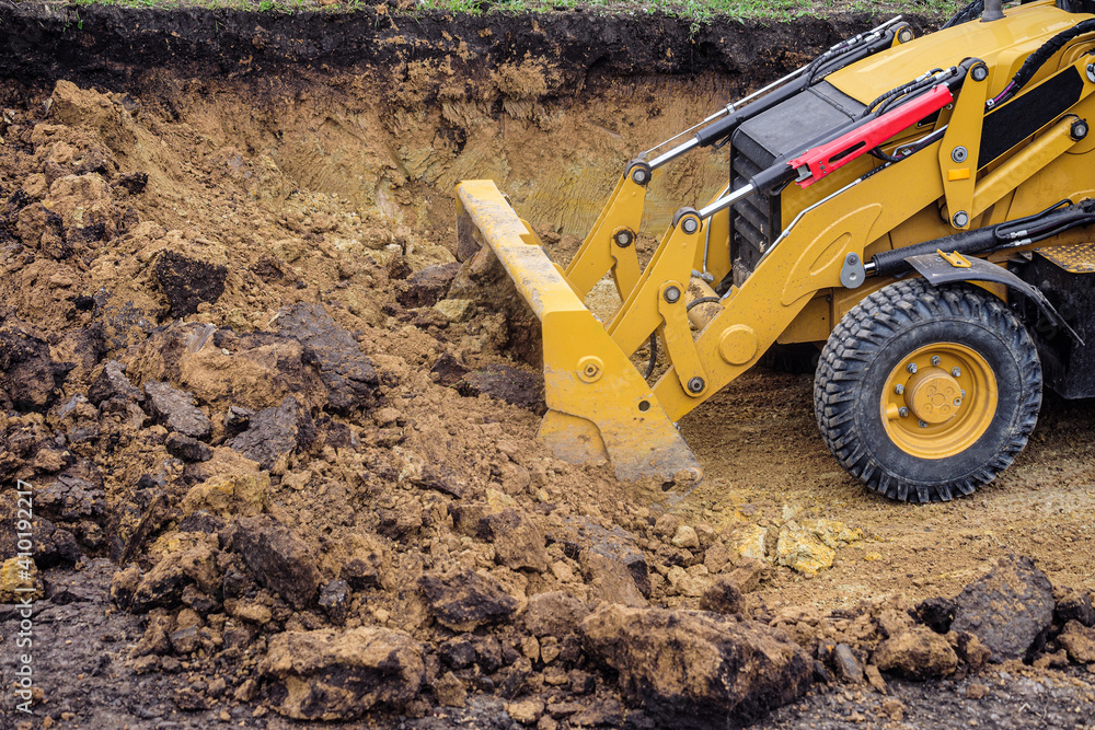 Loader excavator with backhoe planning and cutting clay ground at eathmoving works in construction site quarry Loader excavator with backhoe planning and cutting clay ground at eathmoving works in construction site quarry